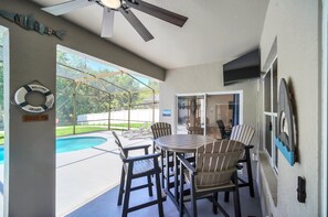 An outdoor patio with a pool, a ceiling fan, and a table with chairs. - EV_5334 - 4 Bed 3 Bath Home with Screened-in Pool, Games Room, Kids Bedrooms (Kissimeee)