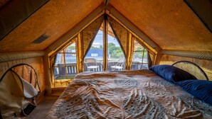 Un dormitorio acogedor en el ático con una cama grande, vistas al exterior y una pequeña mesa con sillas.