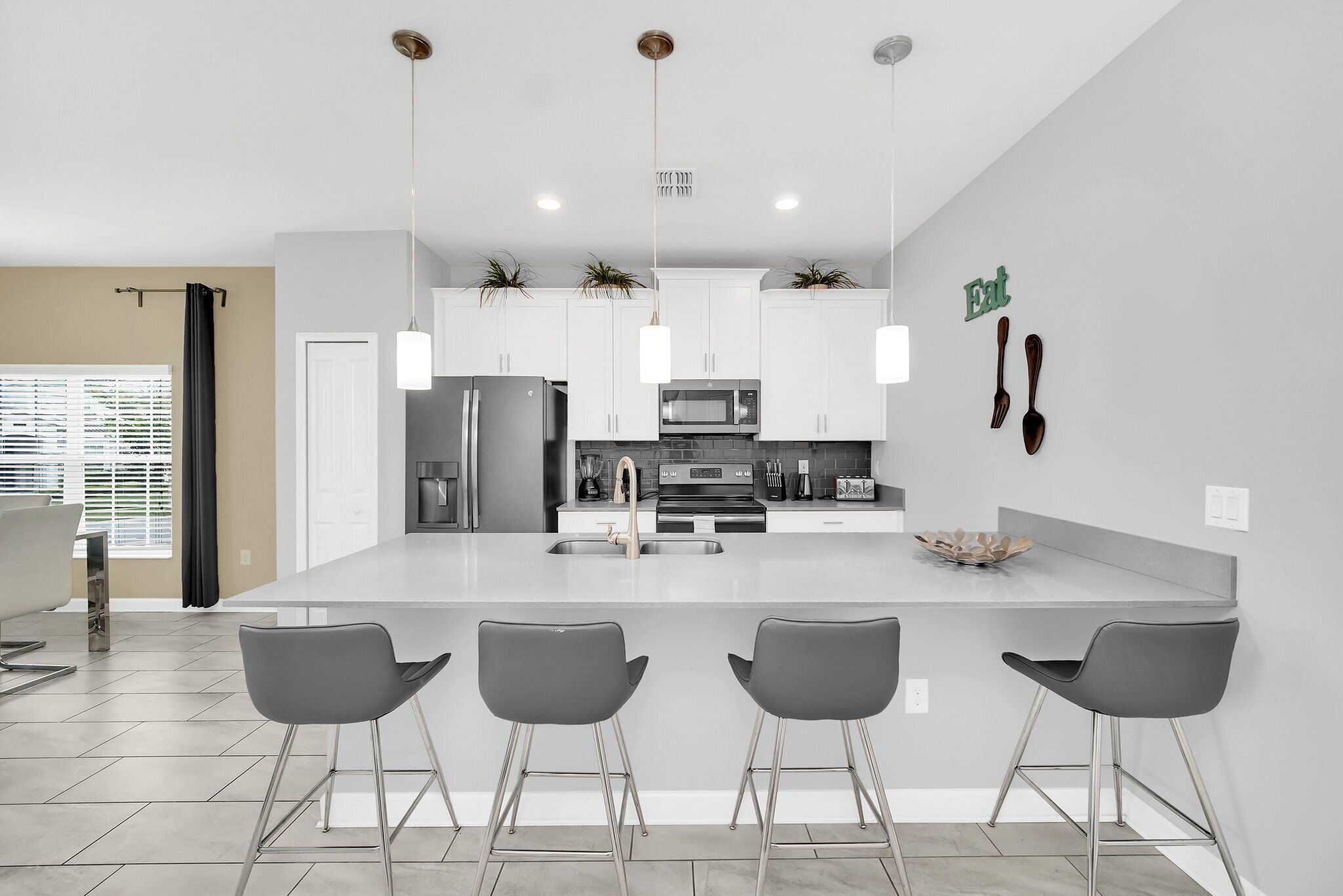 A modern kitchen with white cabinets, stainless steel appliances, and a central island with bar stools.