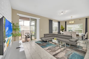 A modern living room with a sectional sofa, a glass coffee table, and a flat-screen TV.