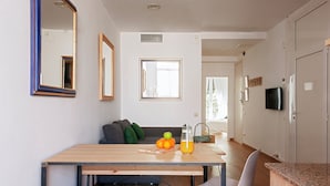 Een moderne keuken met een houten tafel, een televisie en een zithoek met een bank en stoelen.
