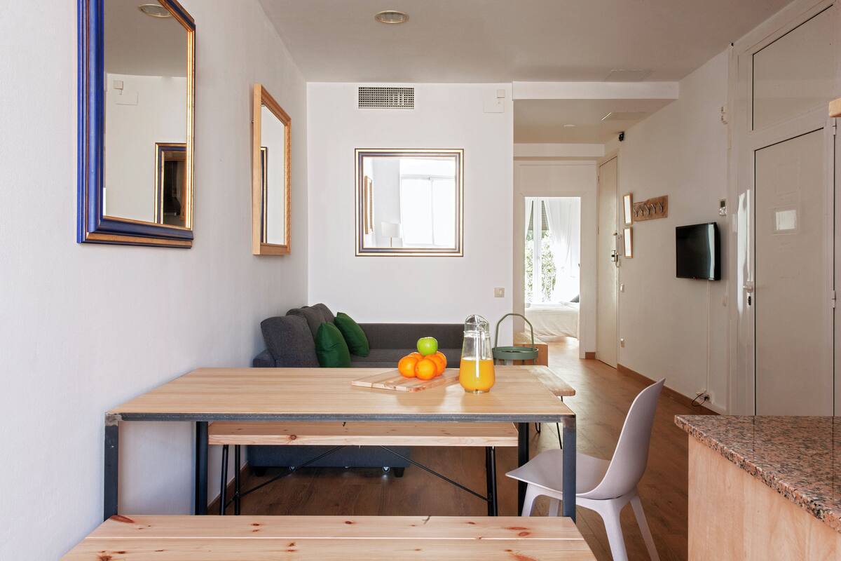 A modern kitchen with a wooden table, a TV, and a dining area with a sofa and chairs.