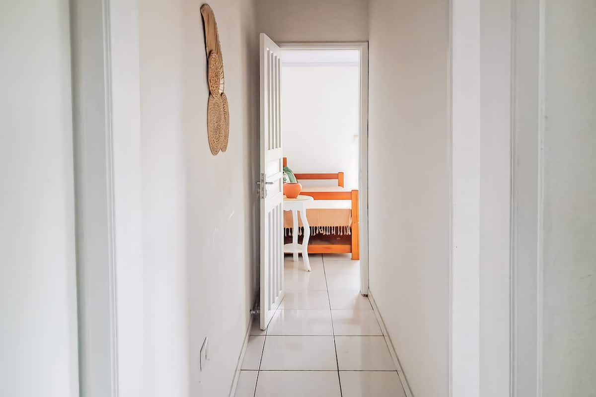 Een gang die leidt naar een kamer met een bed, een tafeltje en een stoel.