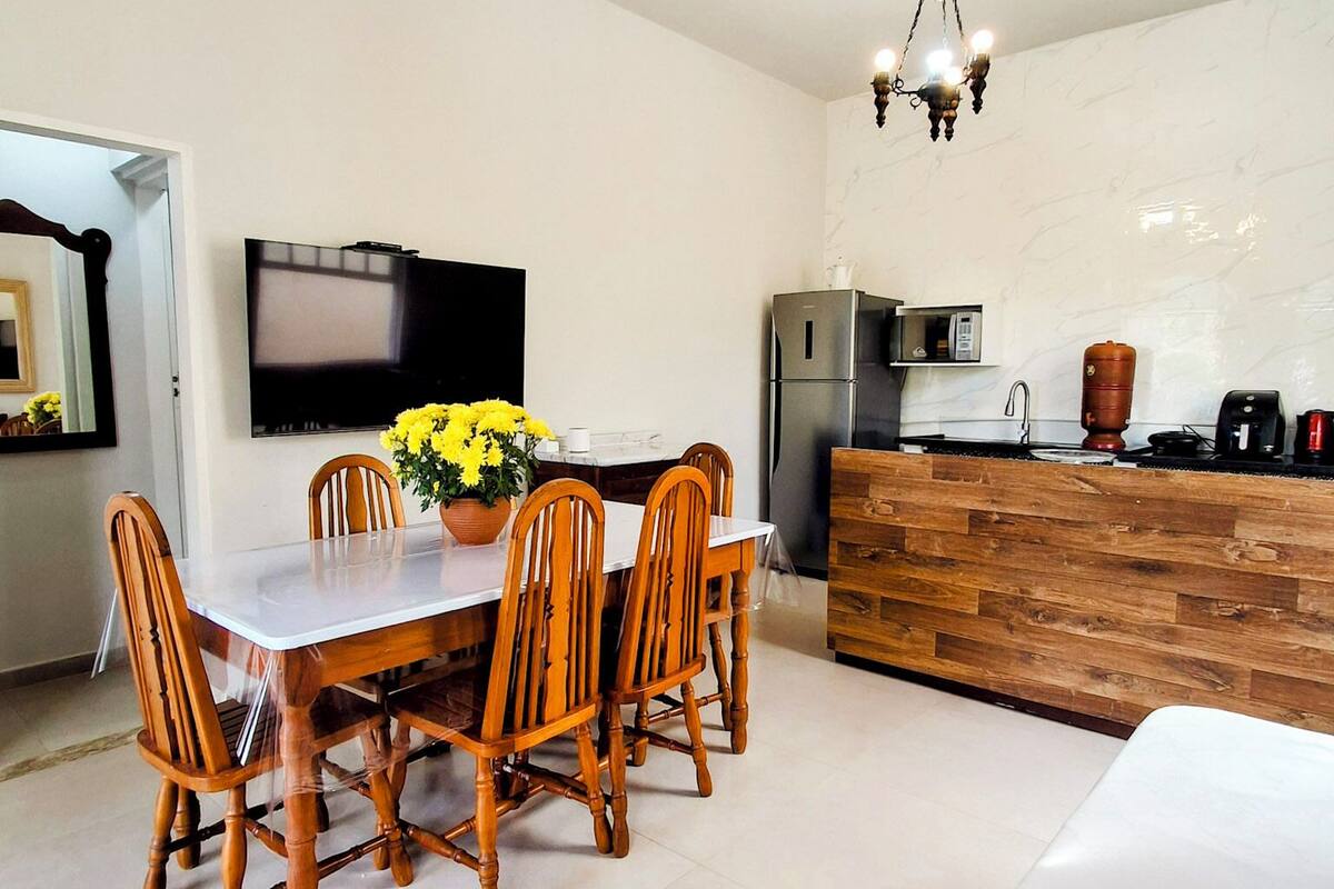 Een moderne keuken met een eethoek, inclusief een houten tafel en stoelen, een televisie en een koelkast.