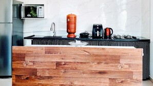 Une cuisine moderne dotée d’un îlot central en bois, d’appareils électroménagers en acier inoxydable et d’un dosseret en marbre.