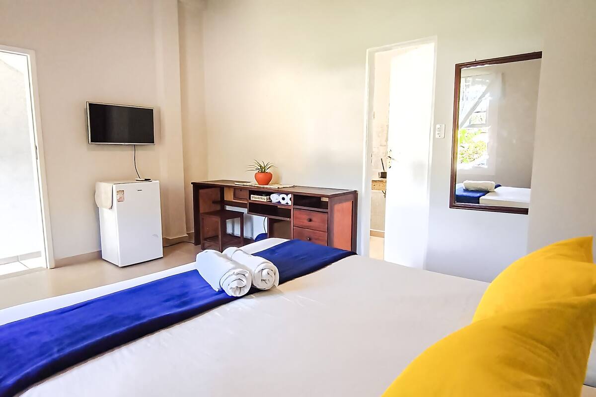 Een hotelkamer met een bed, bureau, televisie en raam.