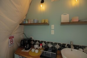 Eine Küche mit Holzausziehtisch, Spüle, Kaffeemaschine und Regalen mit Küchenutensilien.