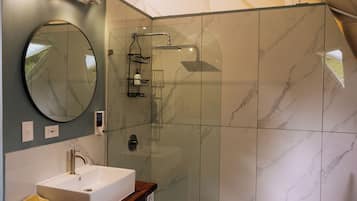 Un bagno moderno con doccia in marmo, lavabo con piano in legno e un grande specchio.