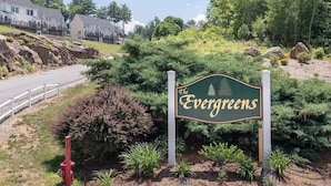 Un cartel que indica 'The Evergreens', con un jardín ajardinado al frente.