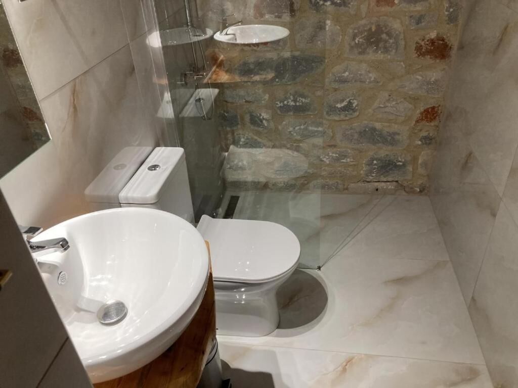 A bathroom with a white sink, toilet, and shower area.