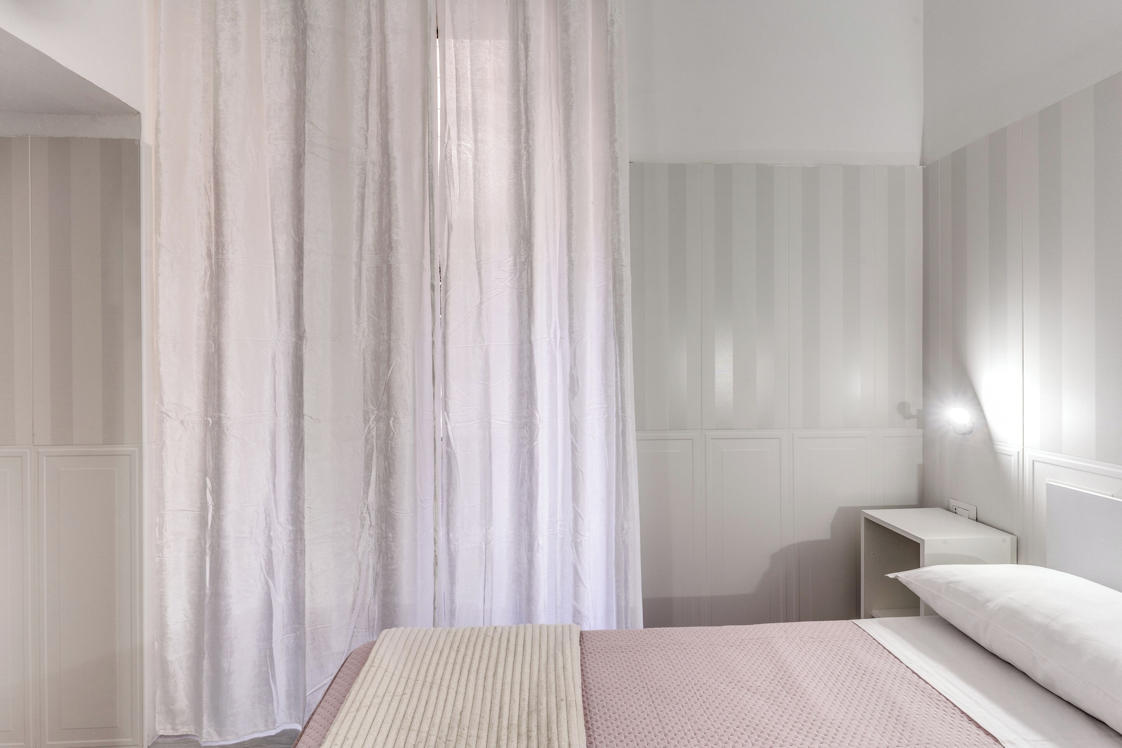 A bedroom with a bed, a bedside table, and a curtain.