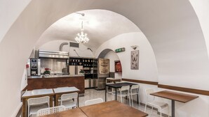 Un café au décor rustique, avec des tables et des chaises en bois, un appareil à café et un lustre.
