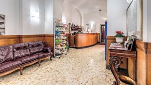 Un hall d’entrée avec un canapé en cuir, un comptoir de réception, une bibliothèque et un sol carrelé.