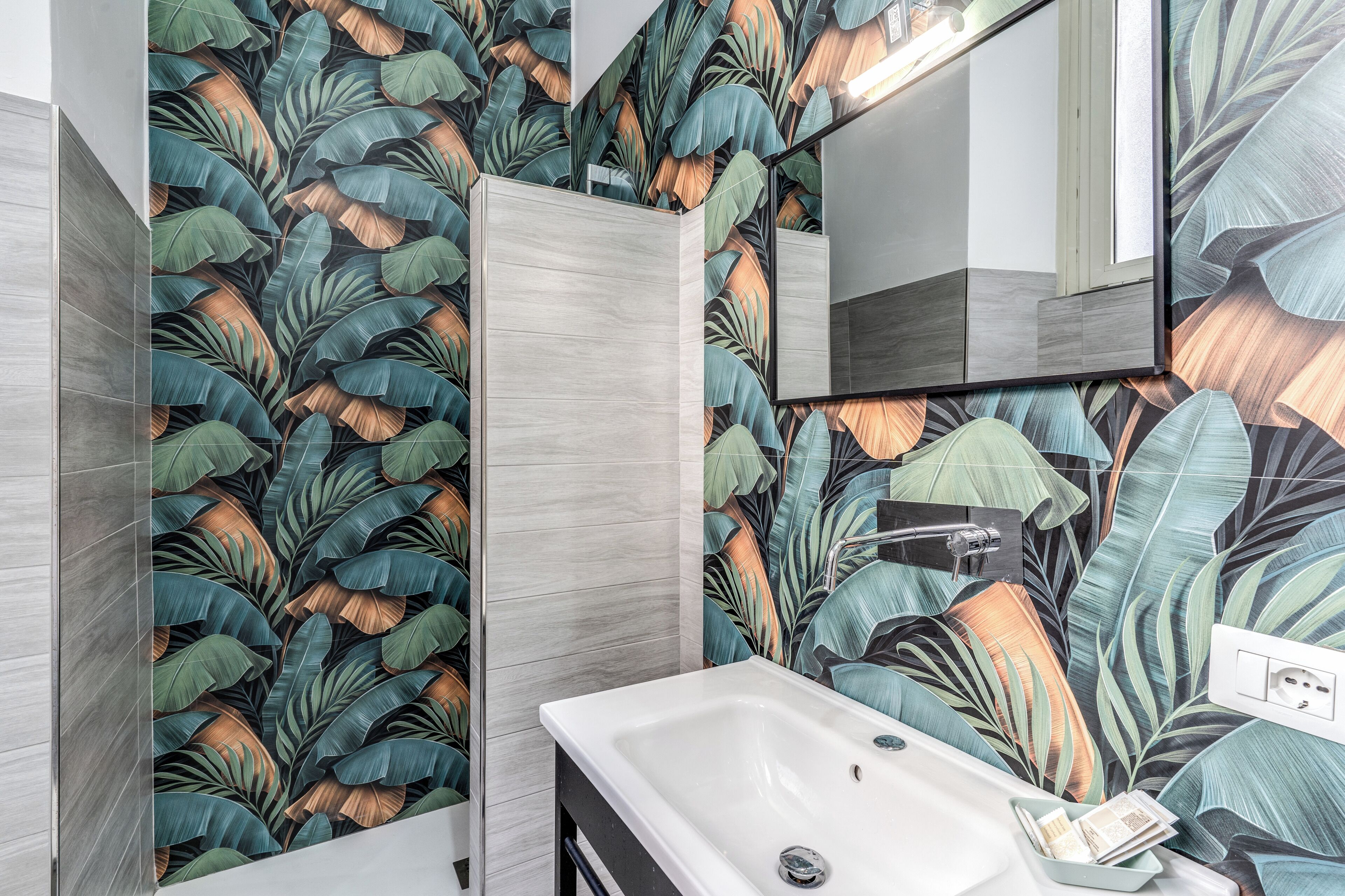 A bathroom with a large mirror, a sink, and a shower area.