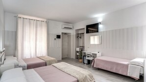 Une chambre d’hôtel avec deux lits simples, un bureau, une chaise, une armoire et un espace douche.