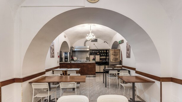 Un restaurant doté d’une cuisine centrale, de chaises blanches et d’un lustre.