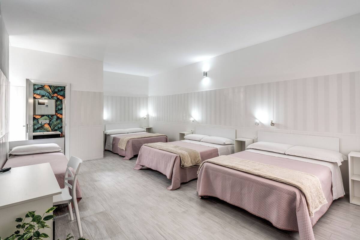 Habitación de hotel con tres camas, un escritorio y una silla.