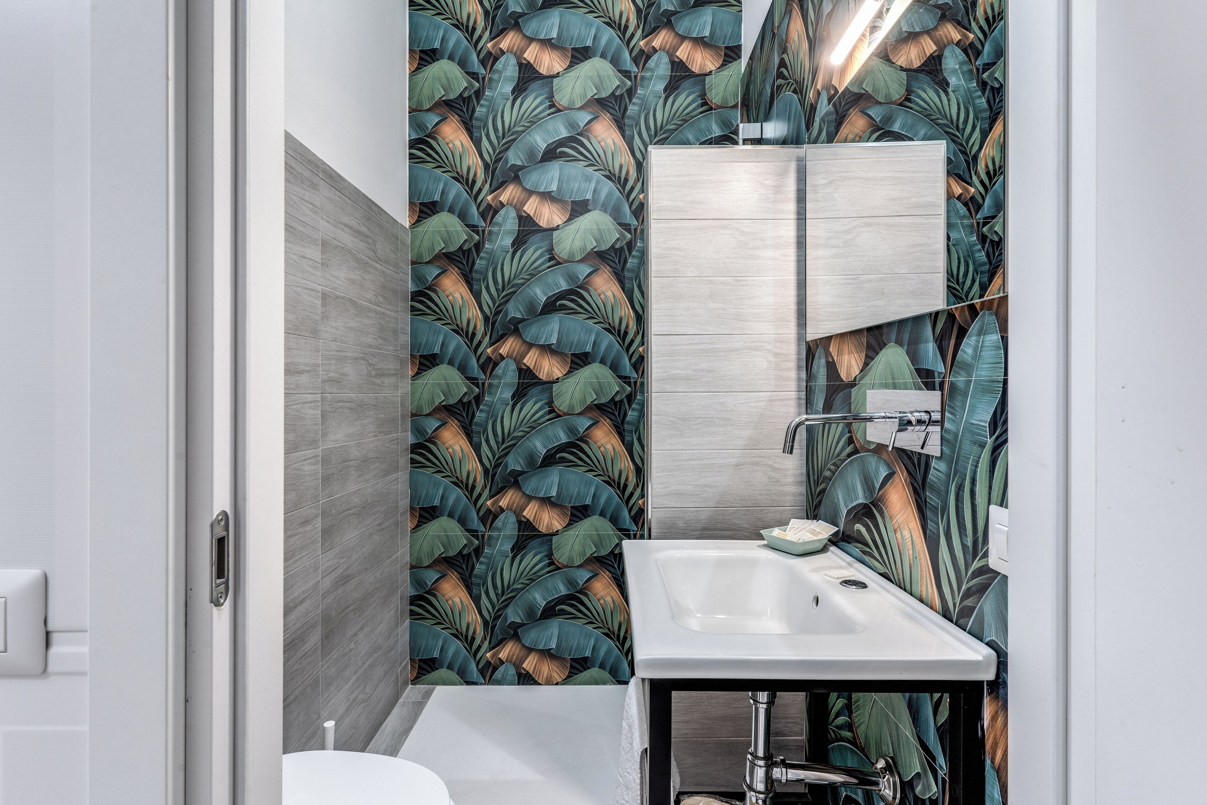 Un bagno con un lavabo moderno, uno specchio e un box doccia.