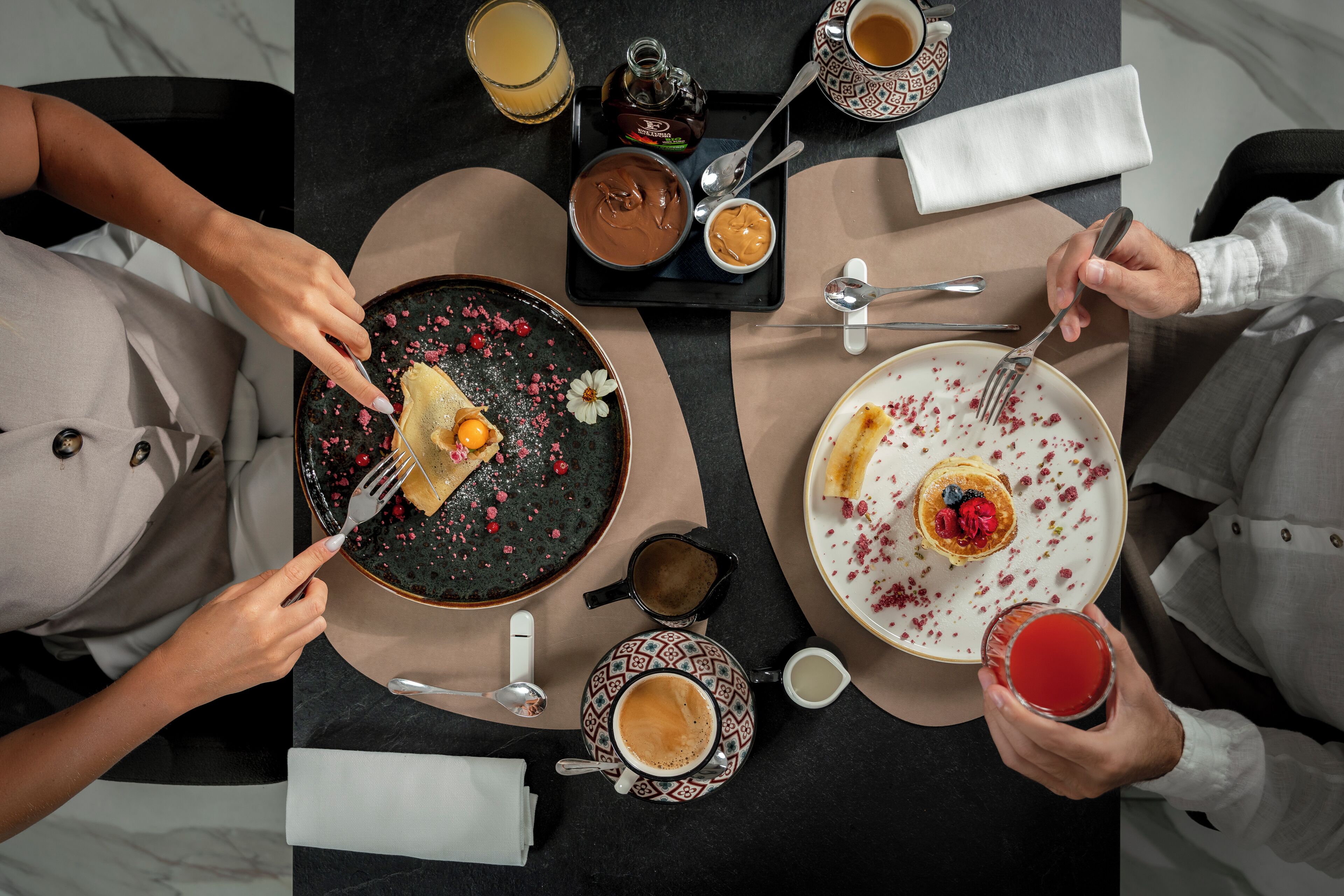A dining table with various dishes, including a plate with a dessert, a cup of coffee, and a glass of red beverage.