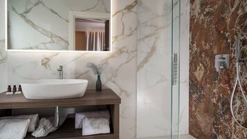 Un baño moderno con un lavamanos grande y blanco, un espejo y una cabina de ducha con mampara de vidrio.