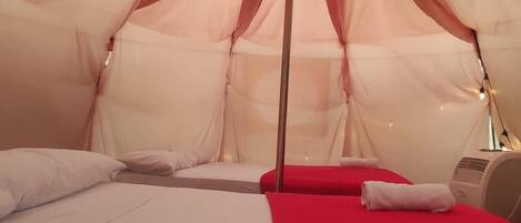 A tent with a bed and a red blanket.