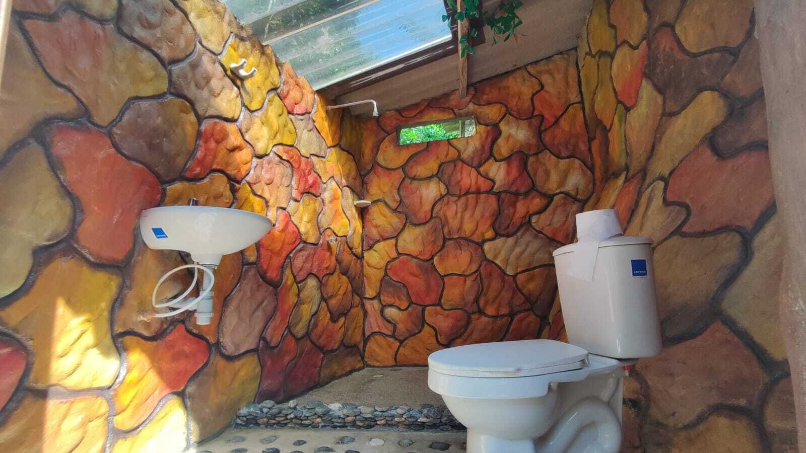Ein Badezimmer mit Steinwand, Waschbecken und Toilette.