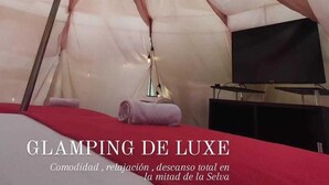 Een tentvormige kamer met een bed, een televisie en een lamp.