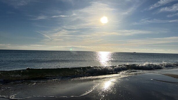 Een strand met golven en een heldere lucht.