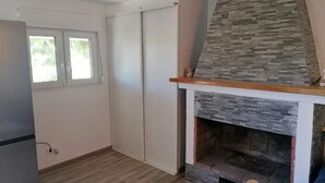 Een kamer met een stenen open haard, een raam en een schuifdeur.