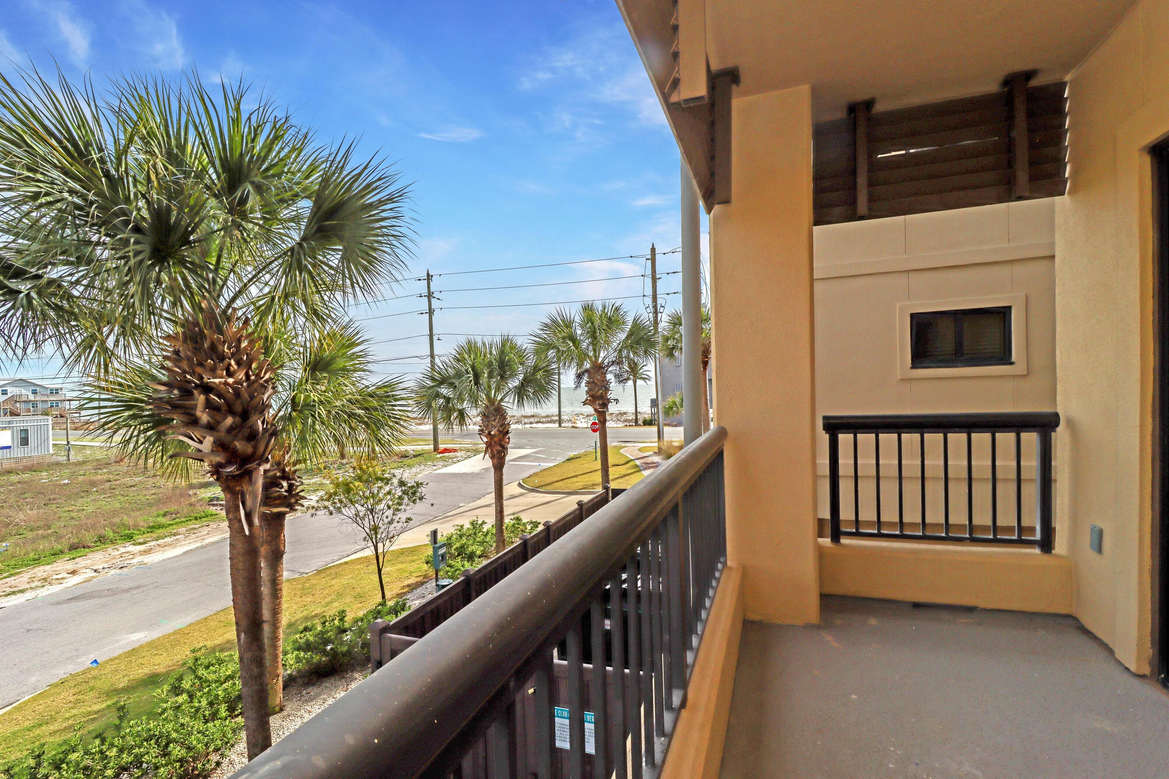A balcony with a view of palm trees and a road.