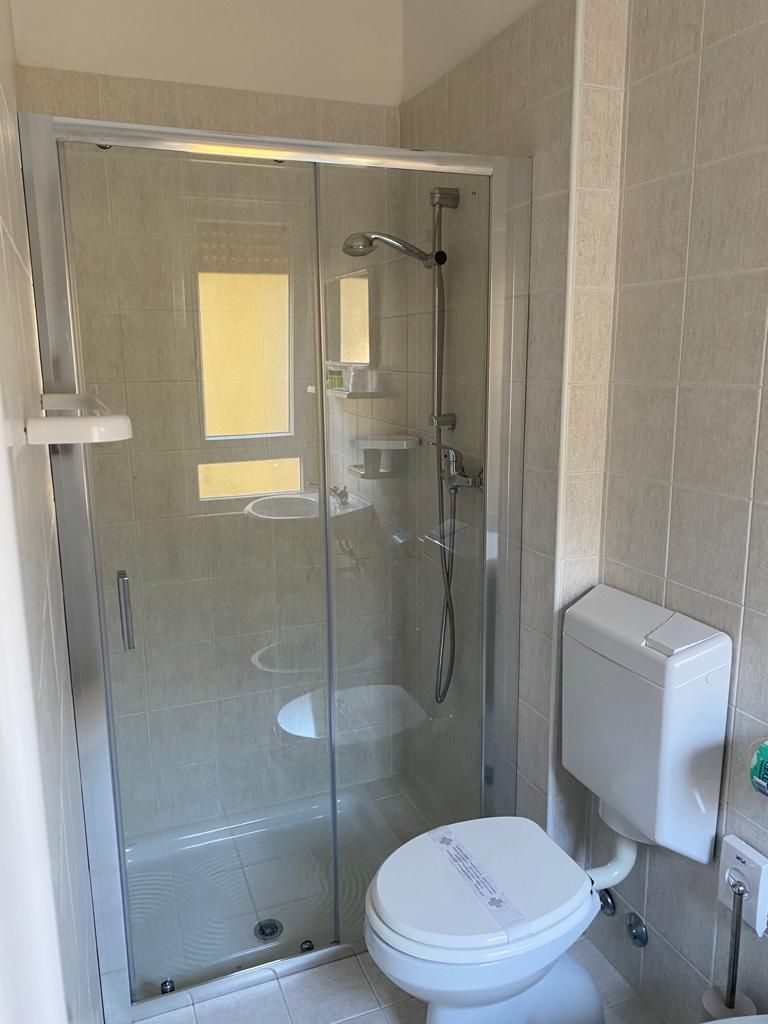 A bathroom with a glass-enclosed shower, a toilet, and a sink.