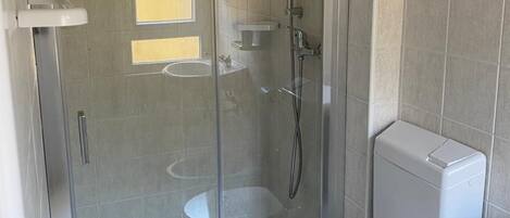 A bathroom with a glass-enclosed shower, a toilet, and a sink.