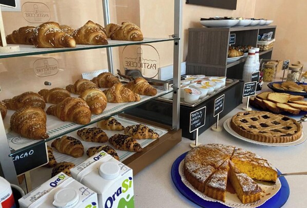 A bakery display with various pastries and a pie on a counter. - HC Resort (Lignano Sabbiadoro)