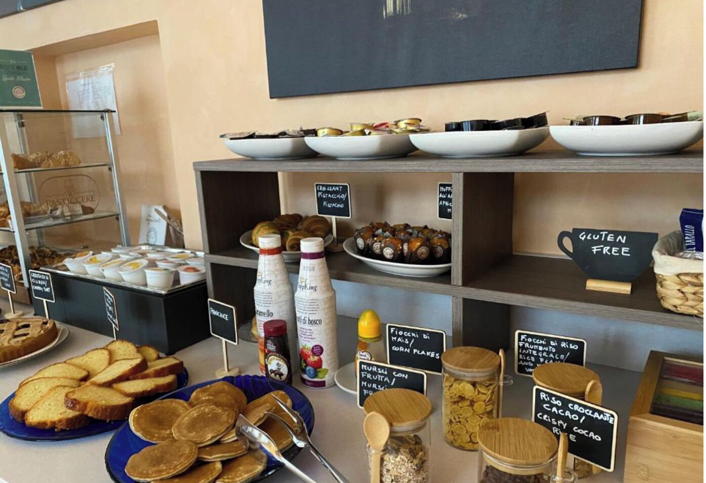 Ein Frühstücksbuffet mit verschiedenen Speisen und Schildern, die glutenfreie Optionen kennzeichnen.