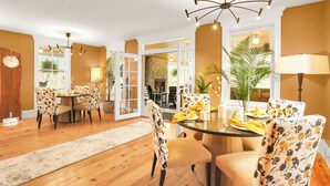 A dining area with a round table, floral chairs, and a chandelier. - Royal Manor Inn (Niagara-on-the-Lake)