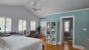 A spacious bedroom with a large bed, a ceiling fan, and a view of the bathroom through an open door. - Royal Manor Inn (Niagara-on-the-Lake)