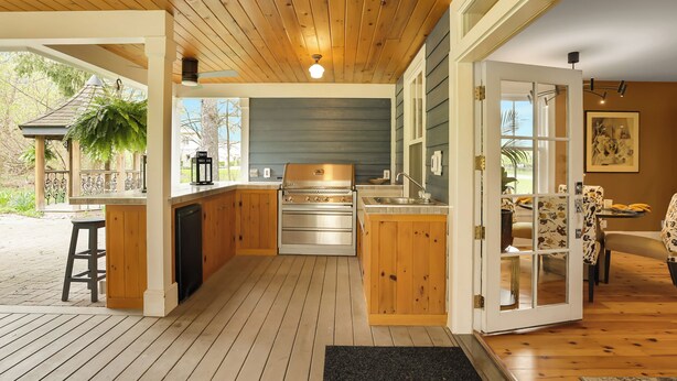 A kitchen with wooden cabinets, a stainless steel stove, and a large window. - Royal Manor Inn (Niagara-on-the-Lake)