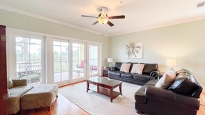 A spacious living room with a large sofa, a coffee table, and a ceiling fan. - Club at Cape San Blas A3 - Shell Seeker (Port St. Joe)