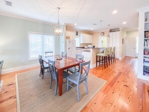 A spacious kitchen with wooden flooring, white cabinets, and a central island with bar stools. - Club at Cape San Blas A3 - Shell Seeker (Port St. Joe)
