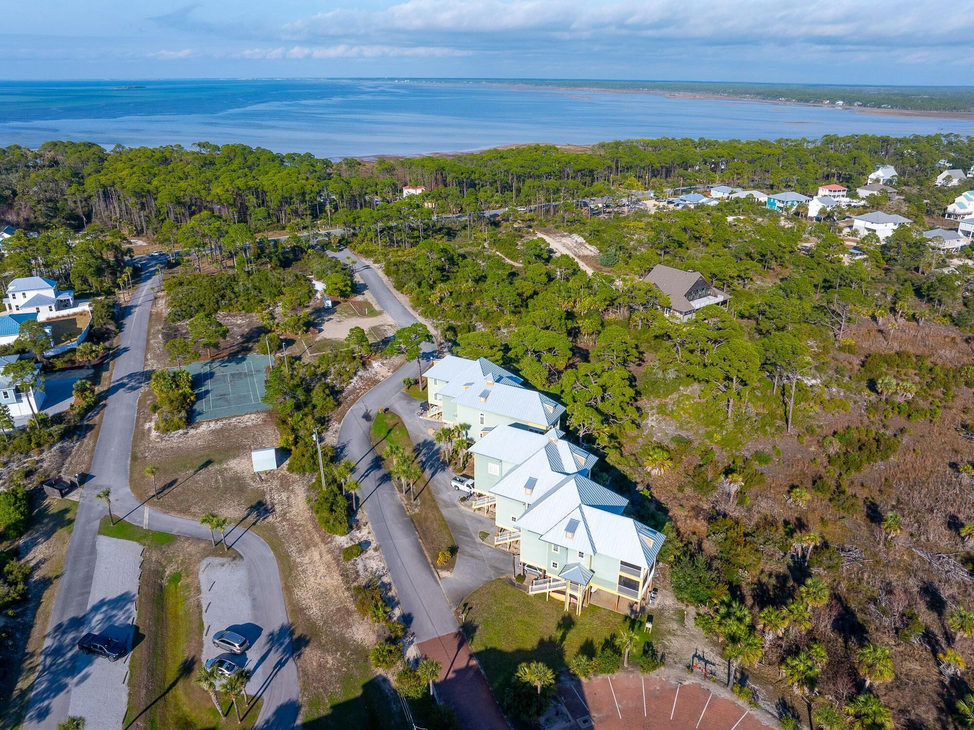 Vue aérienne d’un quartier résidentiel avec des maisons, des routes et une plage en arrière-plan.