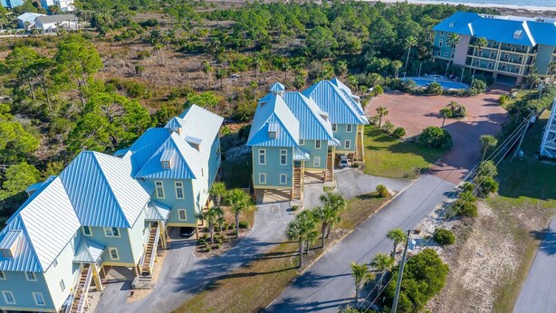 A coastal hotel with multiple blue-roofed buildings, a parking area, and a view of the ocean. - Club at Cape San Blas A3 - Shell Seeker (Port St. Joe)