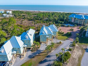 A coastal hotel with multiple blue-roofed buildings, a parking area, and a view of the ocean. - Club at Cape San Blas A3 - Shell Seeker (Port St. Joe)