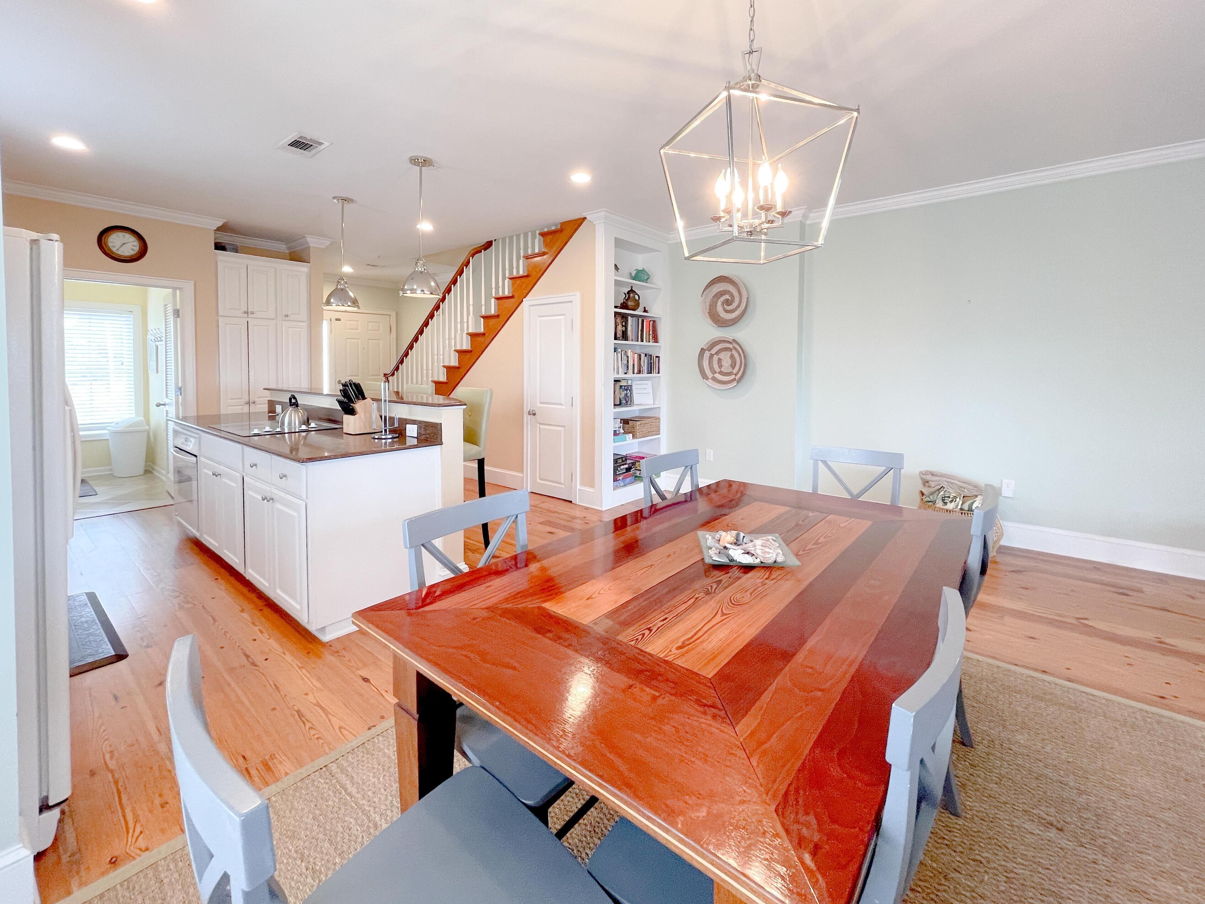 A modern kitchen with white cabinetry, a wooden island, and a dining area with a large wooden table and chairs.
