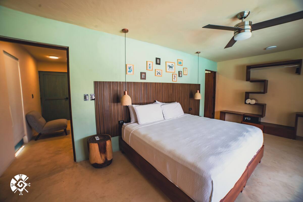 A bedroom with a bed, bedside lamps, a ceiling fan, and framed pictures on the wall.