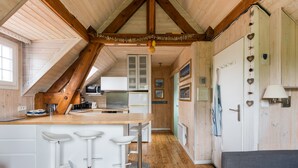 Une cuisine avec un plafond en bois, des armoires blanches et un îlot central doté de tabourets de bar.