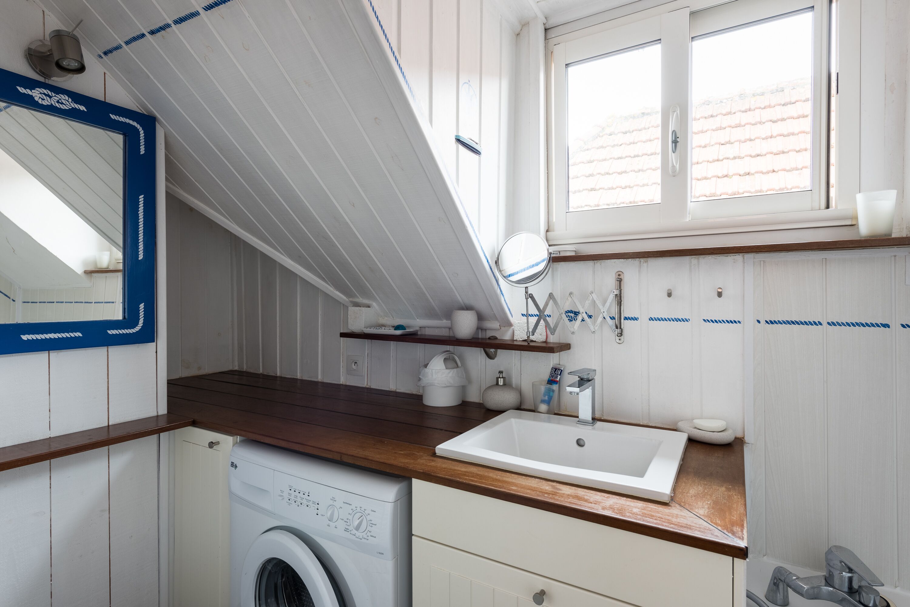 Una cocina compacta con encimera de madera, un lavabo blanco y una lavadora.