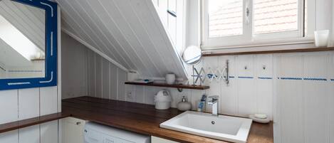 Una cocina compacta con encimera de madera, un lavabo blanco y una lavadora.