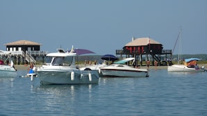 Un port de plaisance où sont amarrés plusieurs bateaux, une structure en bois avec un toit rouge et une zone abritée par des parasols.