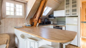 Une cuisine avec des poutres en bois, un plan de travail en bois, des meubles blancs et un four à micro-ondes.