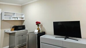 A compact living space with a kitchenette, a flat-screen TV, and a ceiling fan.